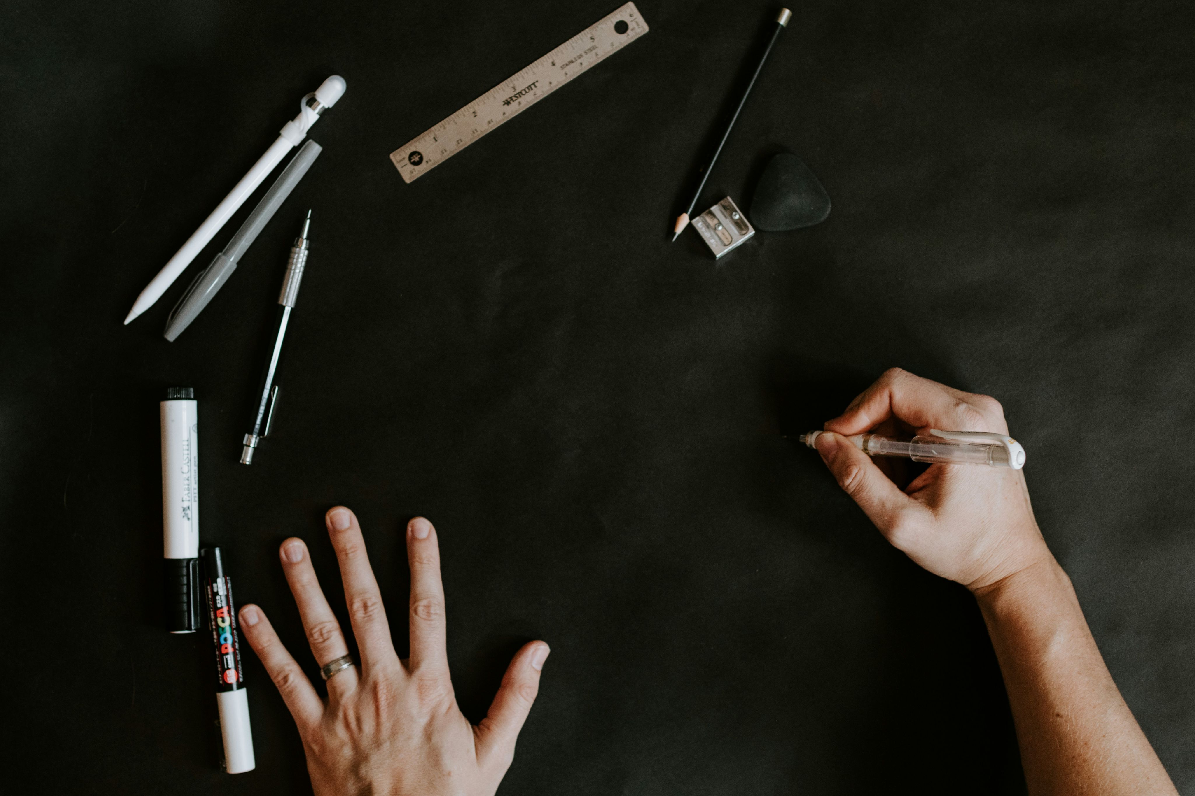 A person's hand reaching for some pens and pencils